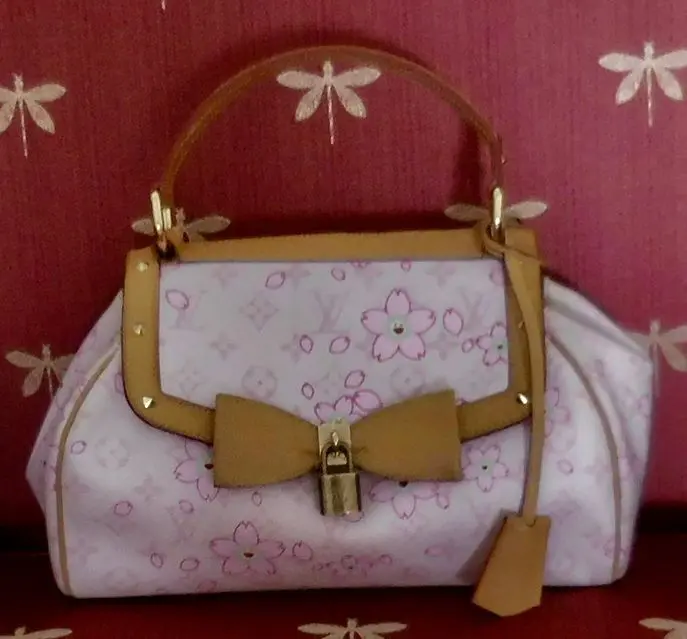 Pink floral handbag with gold lock and bow.