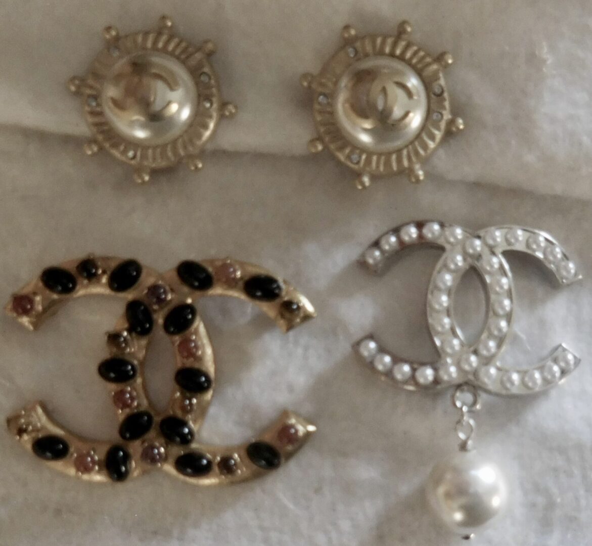 Three Chanel CC logo brooches with pearl accents.